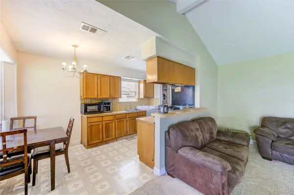 a living room with furniture and a dining table with kitchen appliances