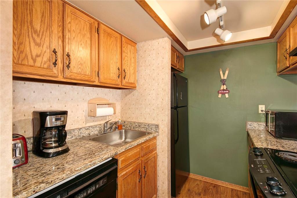 520 Bills Ranch Road, Unit 303 Frisco, CO 80443 - Photo 8 of 25 a kitchen with granite countertop a sink a stove and a wooden cabinets