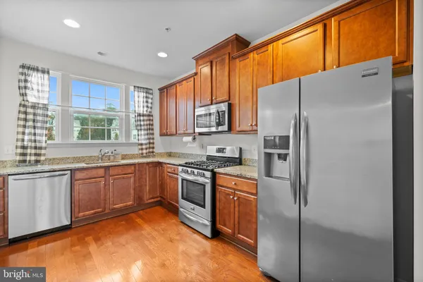 a kitchen with stainless steel appliances granite countertop a refrigerator sink stove microwave and cabinets