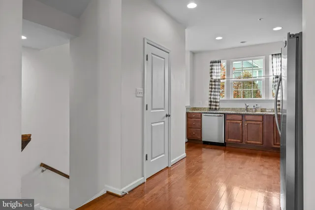 a view of a kitchen with a sink and dishwasher with wooden floor