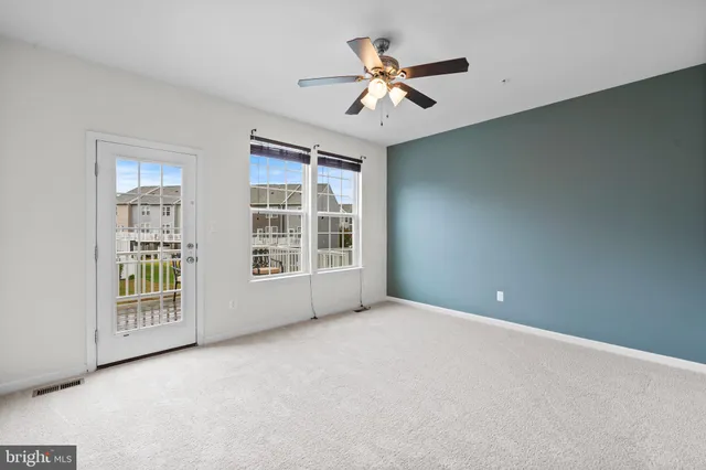 an empty room with windows and chandelier fan