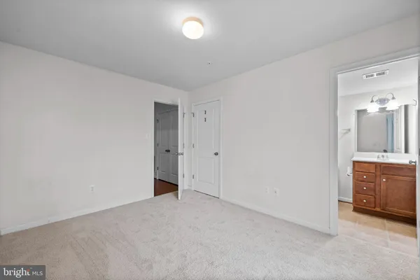 a view of an empty room with window and a kitchen