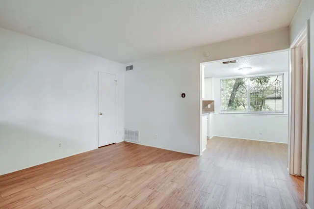 a view of an empty room with wooden floor and a window