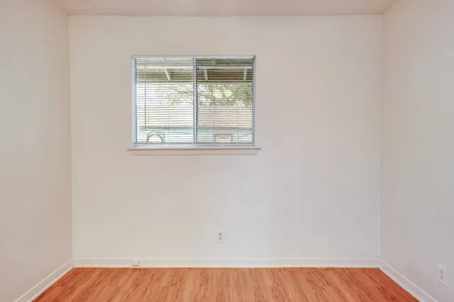 an empty room with wooden floor and a window