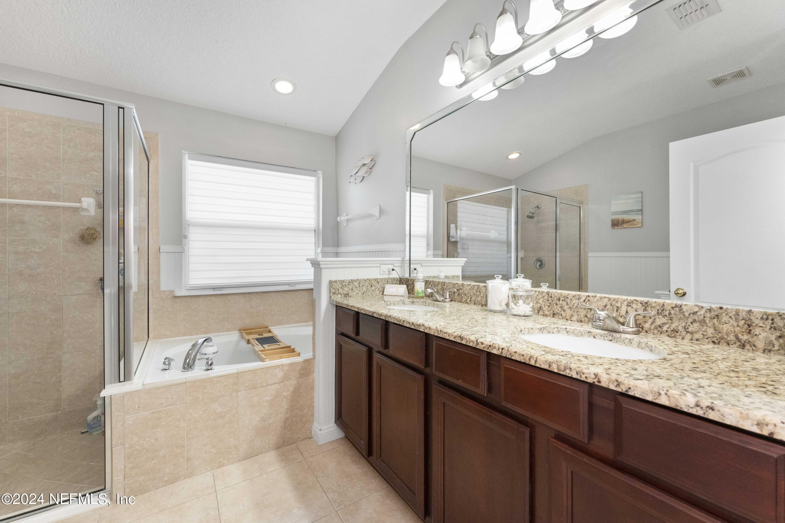 14498 Falling Waters Drive Jacksonville, FL 32258 - Photo 17 of 54 a bathroom with a granite countertop bathtub a sink and a large mirror