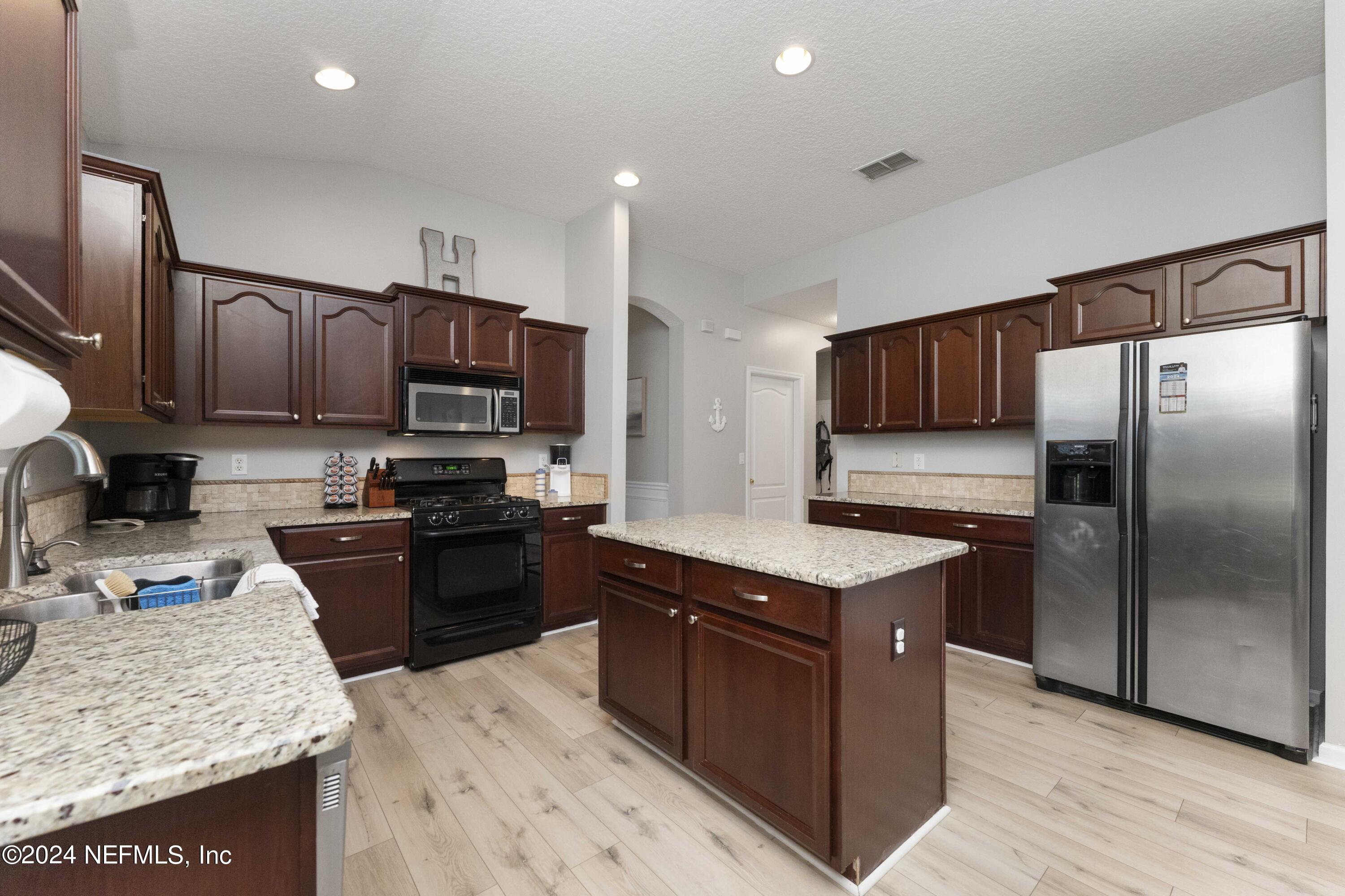 14498 Falling Waters Drive Jacksonville, FL 32258 - Photo 10 of 54 a kitchen with stainless steel appliances granite countertop a stove top oven a sink dishwasher a refrigerator and a microwave oven with large wooden cabinets