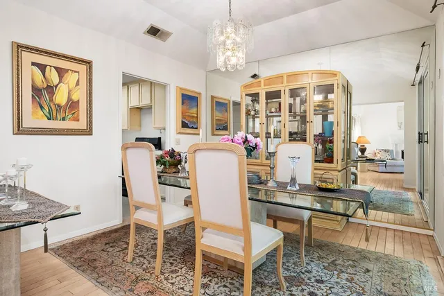 a dining room with wooden floor and large windows