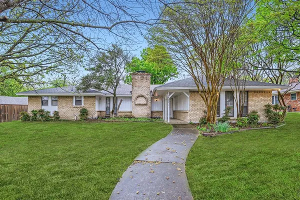a front view of a house with a garden and trees