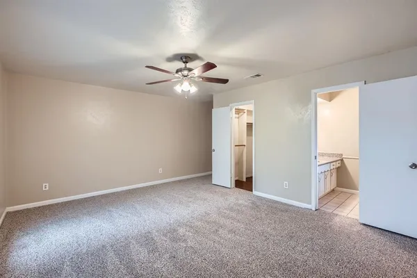an empty room with chandelier fan and windows