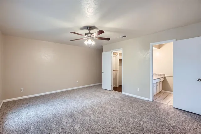 an empty room with chandelier fan and windows