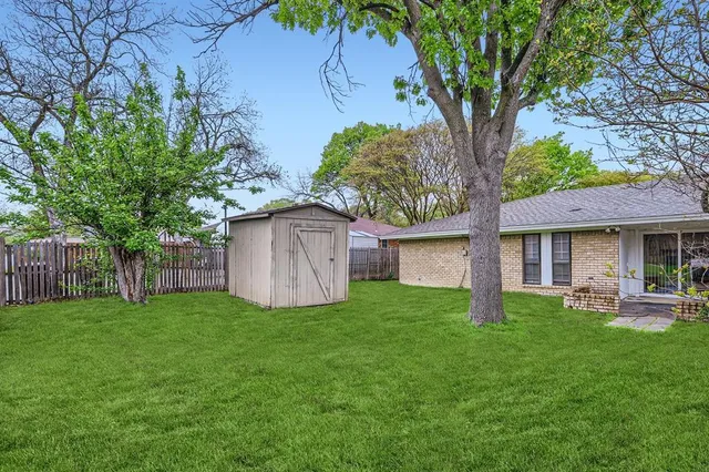 a view of a house with a yard and a large tree