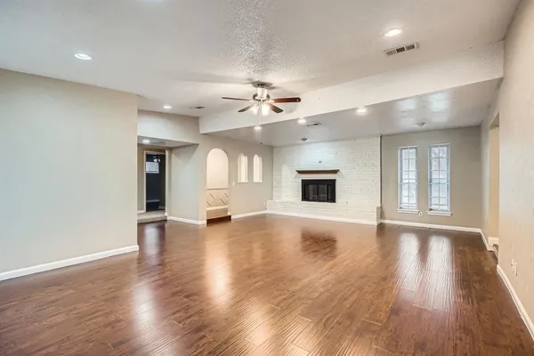 a view of an empty room with window and wooden floor