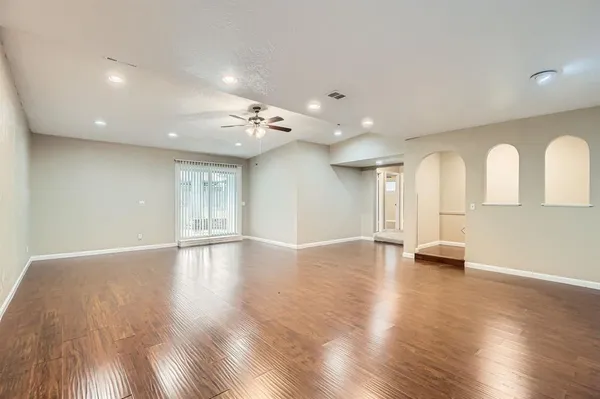 a view of an empty room with wooden floor and a window