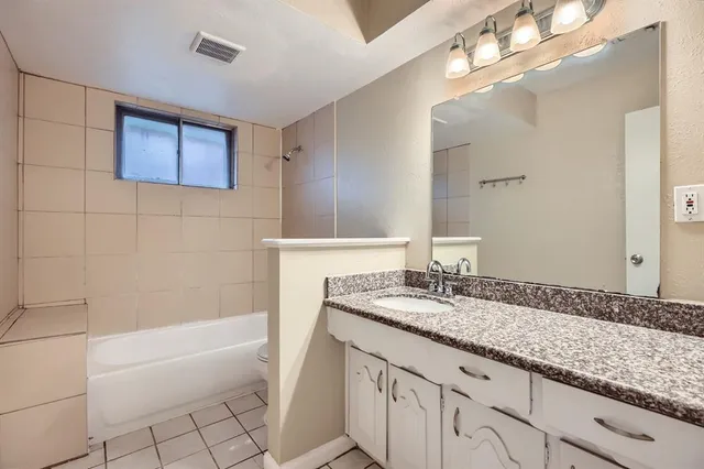 a bathroom with a granite countertop bathtub a sink and a mirror