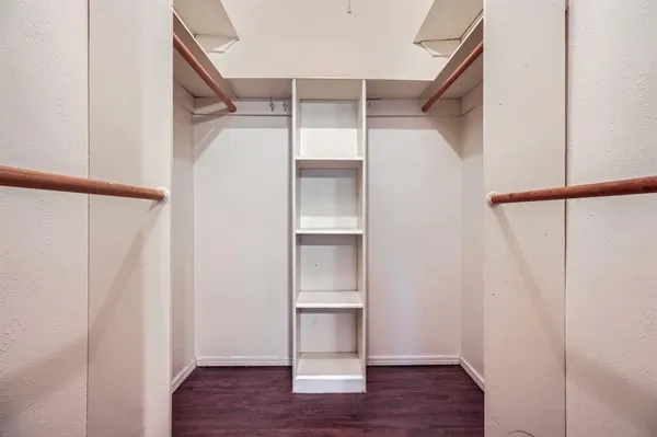 a view of an empty walk in closet with wooden floor