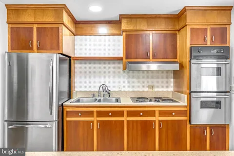 a kitchen with stainless steel appliances granite countertop a refrigerator a stove and a sink with wooden floor