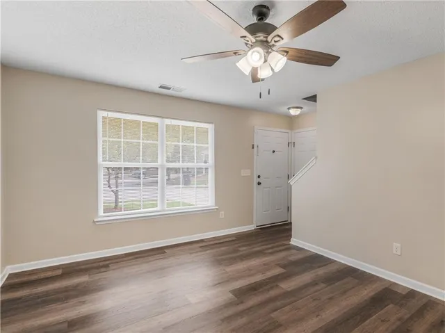 an empty room with wooden floor and windows