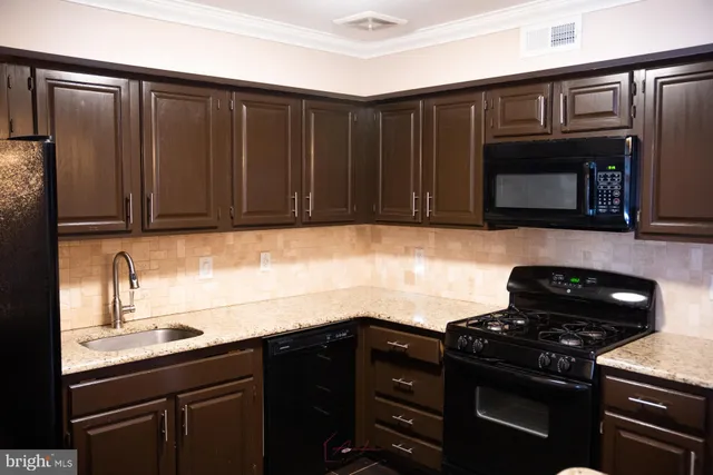 a kitchen with granite countertop cabinets and black appliances
