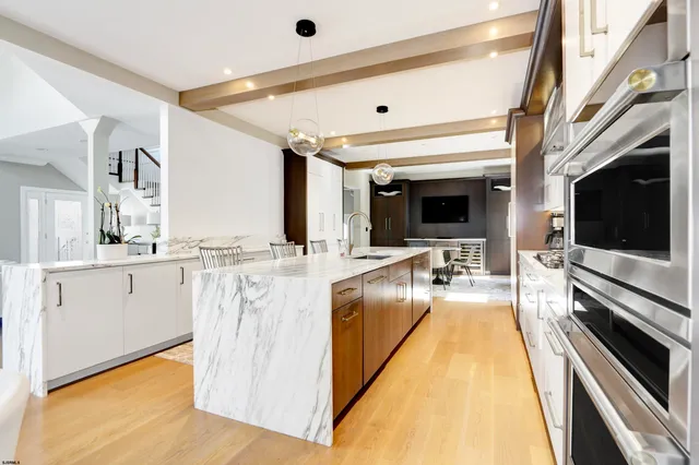 a view of a kitchen with kitchen island wooden floor and stainless steel appliances