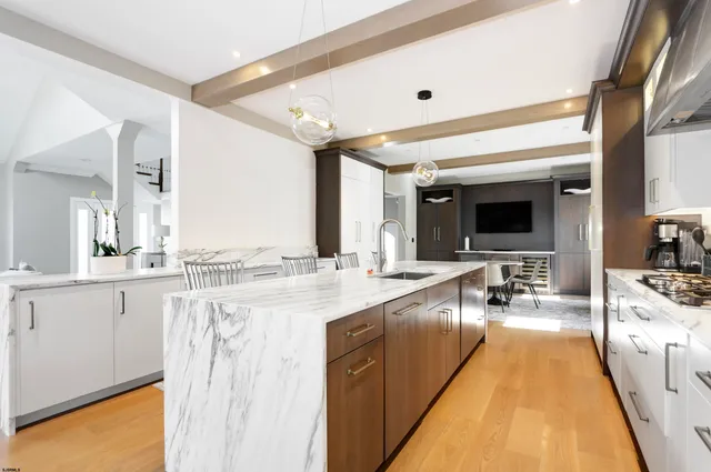 a large kitchen with a large counter top a sink stainless steel appliances and cabinets
