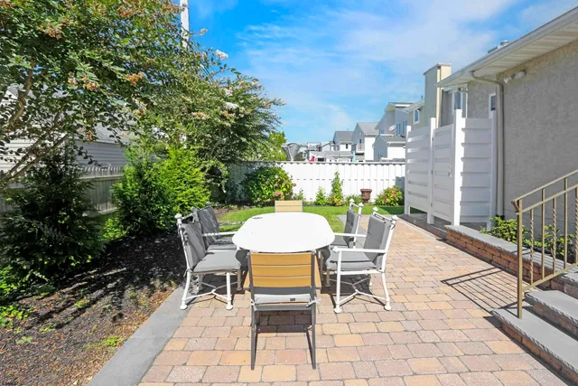 a view of a patio with table and chairs potted plants and large tree