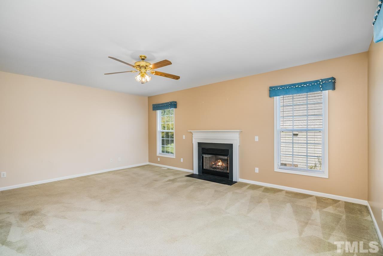 664 Seastone Street Raleigh, NC 27603 - Photo 13 of 25 an empty room with a fireplace and a ceiling fan