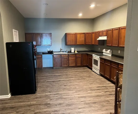 a large kitchen with stainless steel appliances granite countertop a refrigerator a stove a sink and a microwave