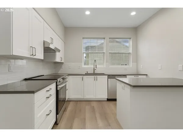 a kitchen with granite countertop a sink stainless steel appliances and cabinets