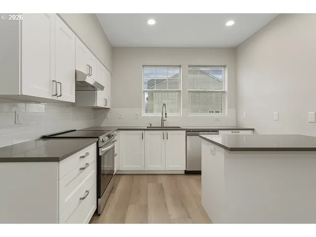 a kitchen with granite countertop a sink stainless steel appliances and cabinets