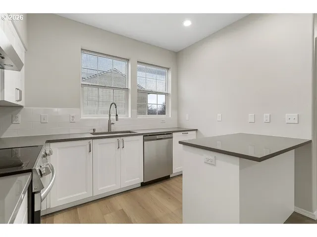 a kitchen with granite countertop cabinets stainless steel appliances a sink and a window