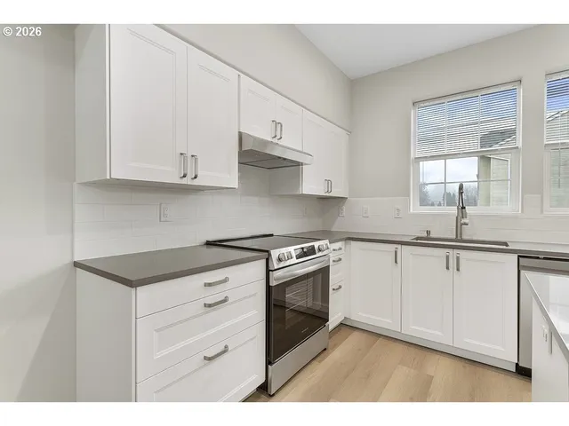 a kitchen with cabinets appliances a sink and a window