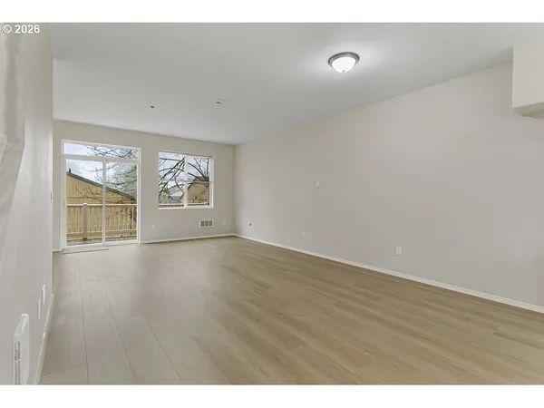 a view of an empty room with wooden floor and windows
