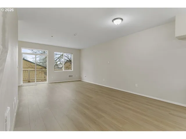 a view of an empty room with wooden floor and windows
