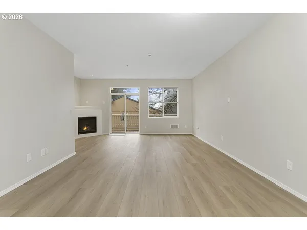a view of empty room with wooden floor and fireplace