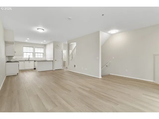 a view of an empty room with wooden floor and windows