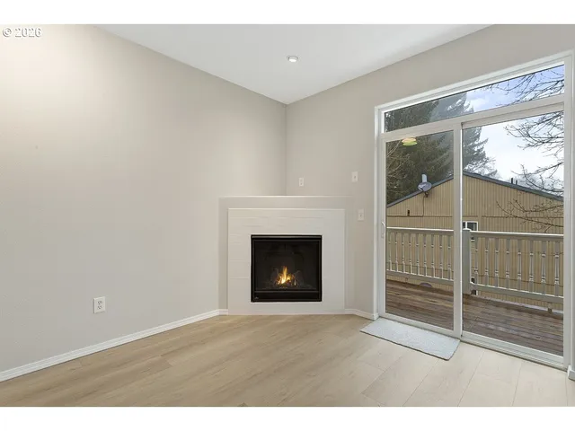 a view of an empty room with a fireplace and window