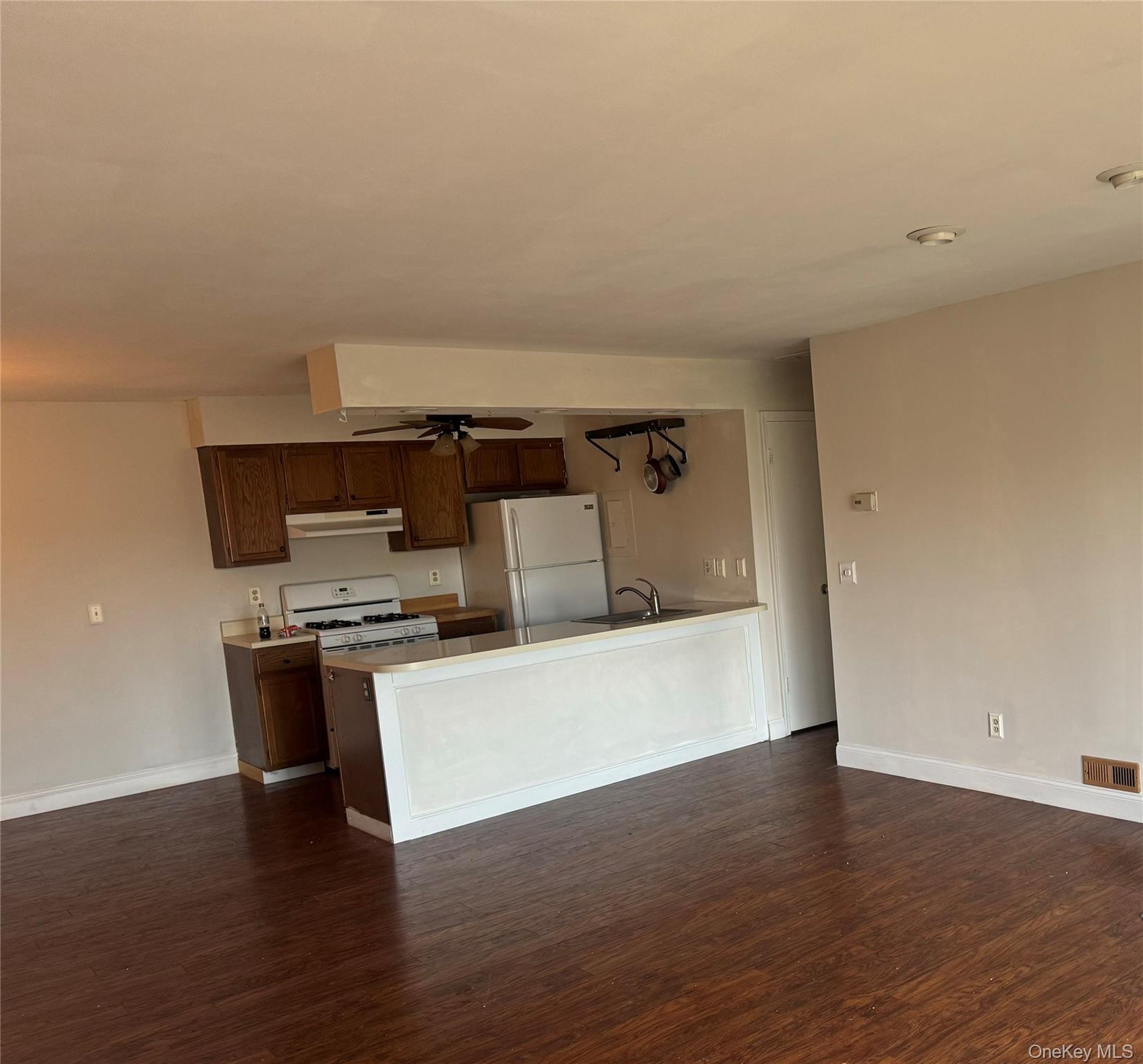 11 The Rise Warwick, NY 10990 - Photo 4 of 11 Kitchen with white appliances, dark wood finished floors, a peninsula, and dark brown cabinets