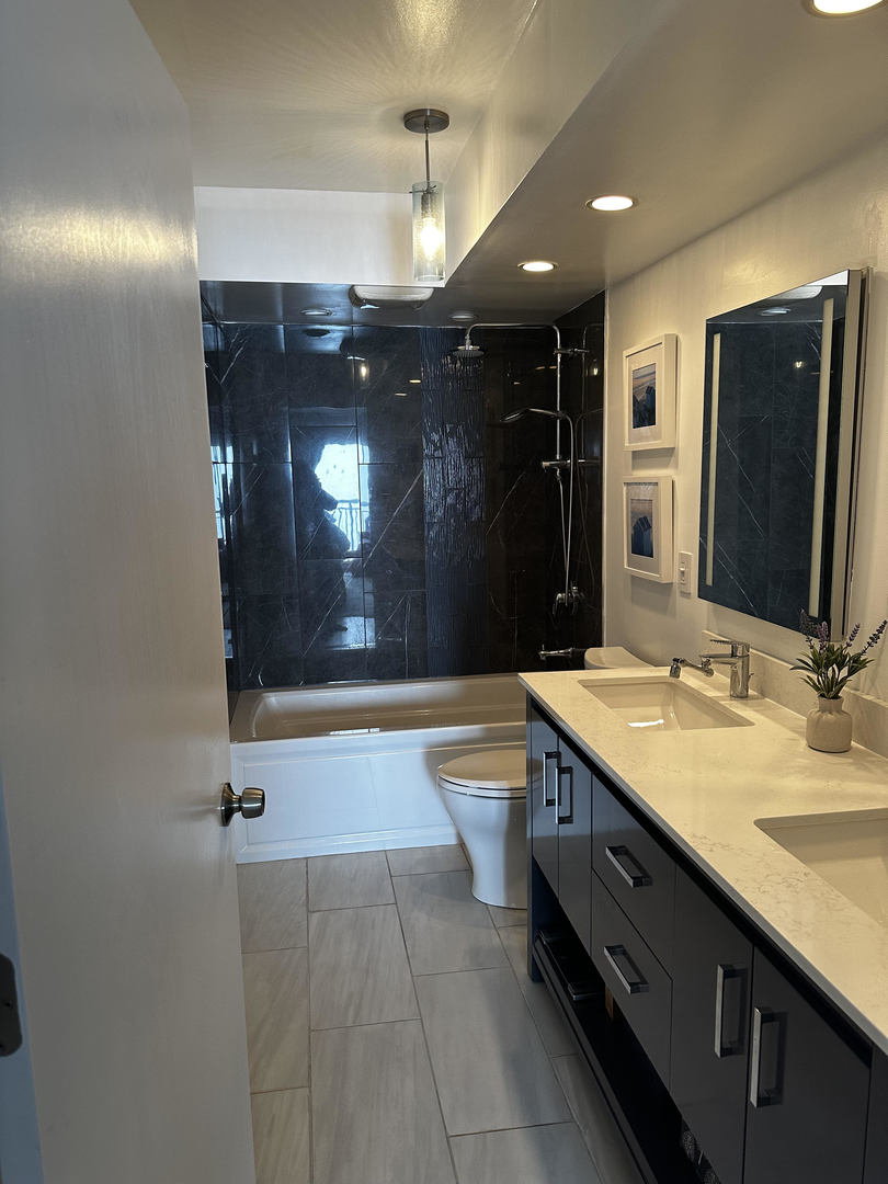 6007 North Sheridan Road, Unit 31A Chicago, IL 60660 - Photo 17 of 19 a bathroom with a sink double vanity granite tub shower and a mirror