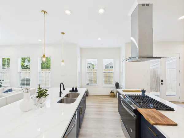 a large kitchen with stainless steel appliances a large counter top a stove and a sink