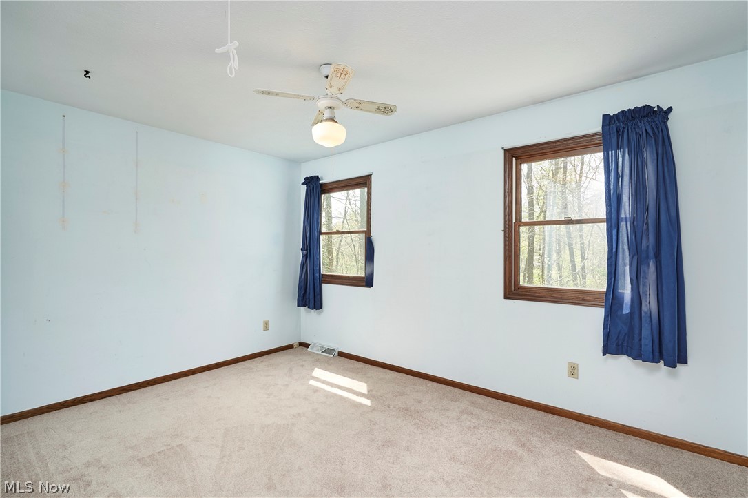 3097 Baughman Road Clinton, OH 44216 - Photo 11 of 27 Bright room featuring two large windows with natural wood trim, plush carpeting, and a ceiling fan with integrated lighting