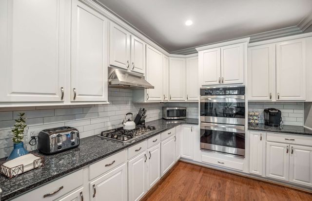 a kitchen with granite countertop white cabinets and white appliances