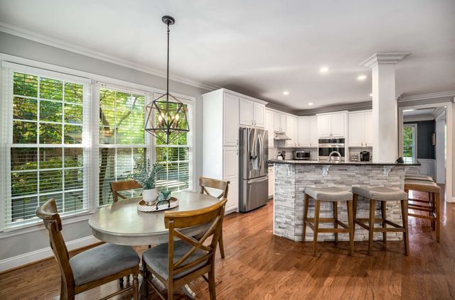 a kitchen with refrigerator a dining table and chairs