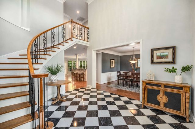 a dining room with a black white checkered floor with couches chair and a coffee table