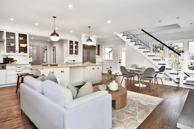 a living room with furniture kitchen view and a wooden floor