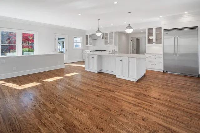 a large kitchen with kitchen island a stove a sink dishwasher and a refrigerator with wooden floor