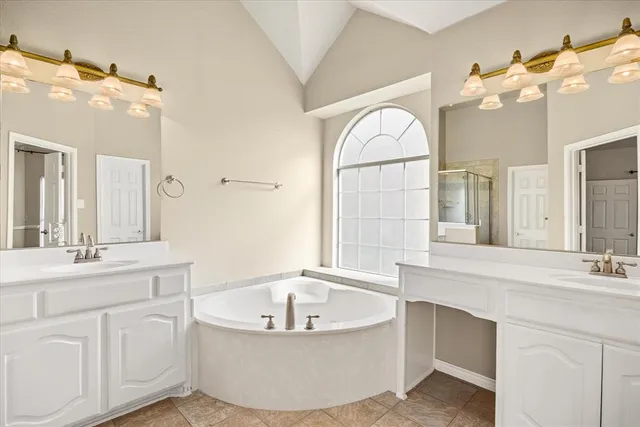 a bathroom with a tub a double vanity sink a mirror a vanity and a bathtub