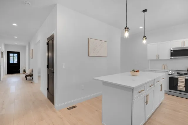a kitchen that has a lot of white cabinets and stainless steel appliances