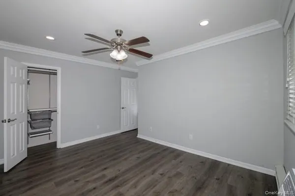 a view of an empty room with wooden floor and a ceiling fan