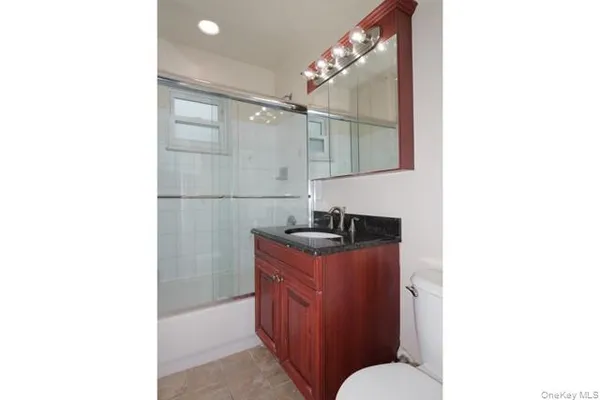 a bathroom with a granite countertop sink a toilet and shower