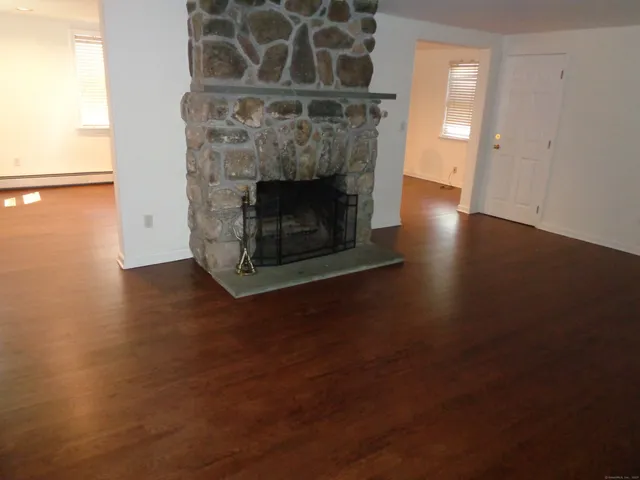 an empty room with wooden floor and a fireplace